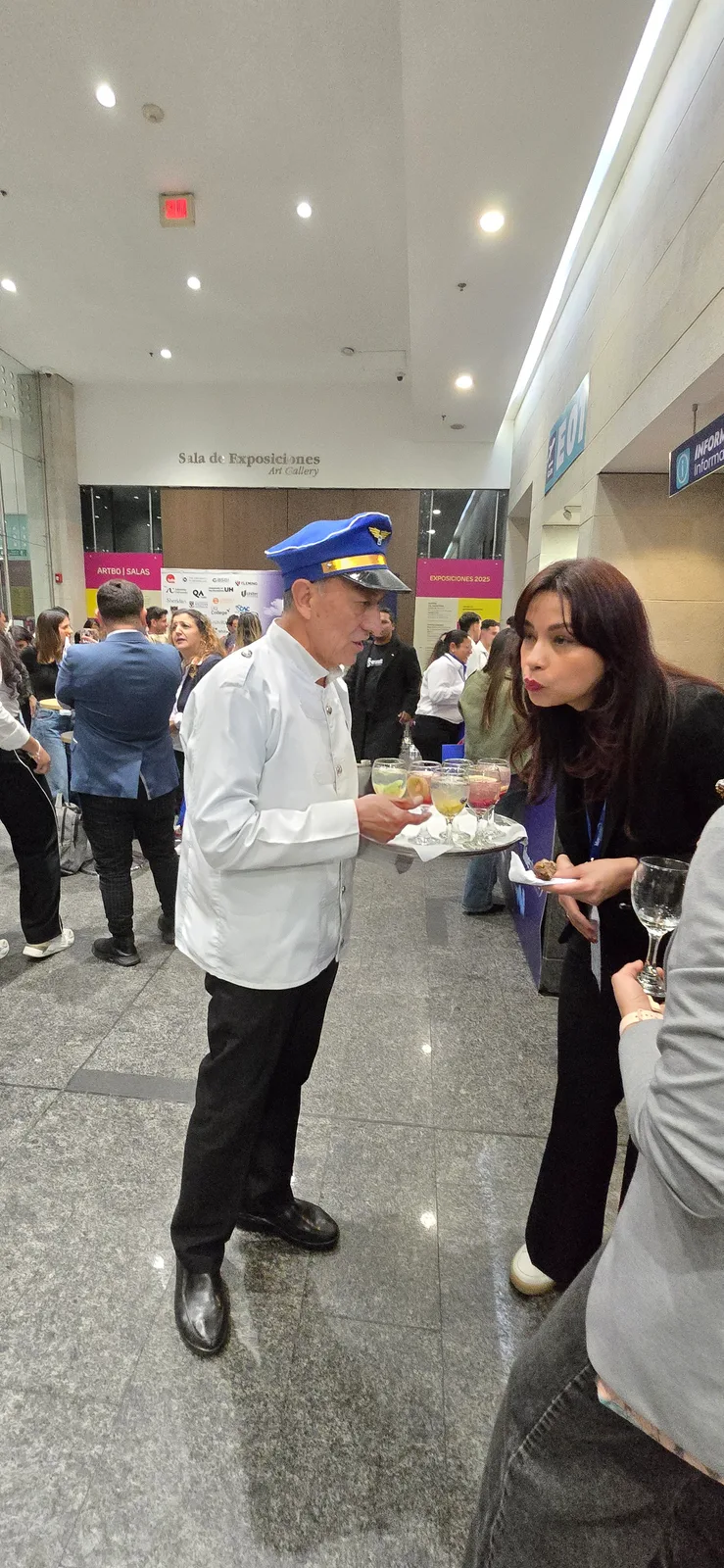 Una persona del equipo de servicio ofrece alimentos a los asistentes.