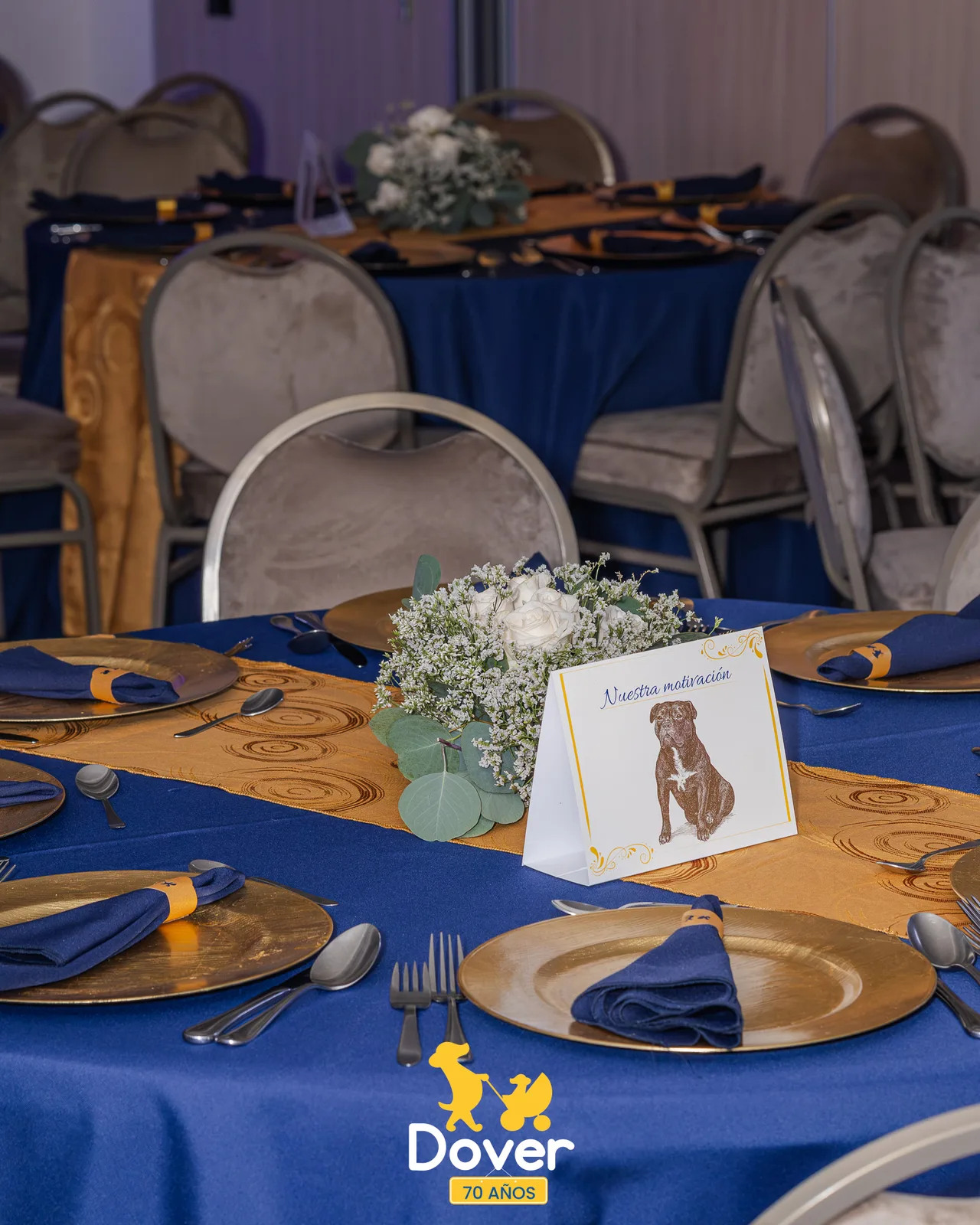 Mesa de celebración con vajilla, flores y detalles en azul y dorado.